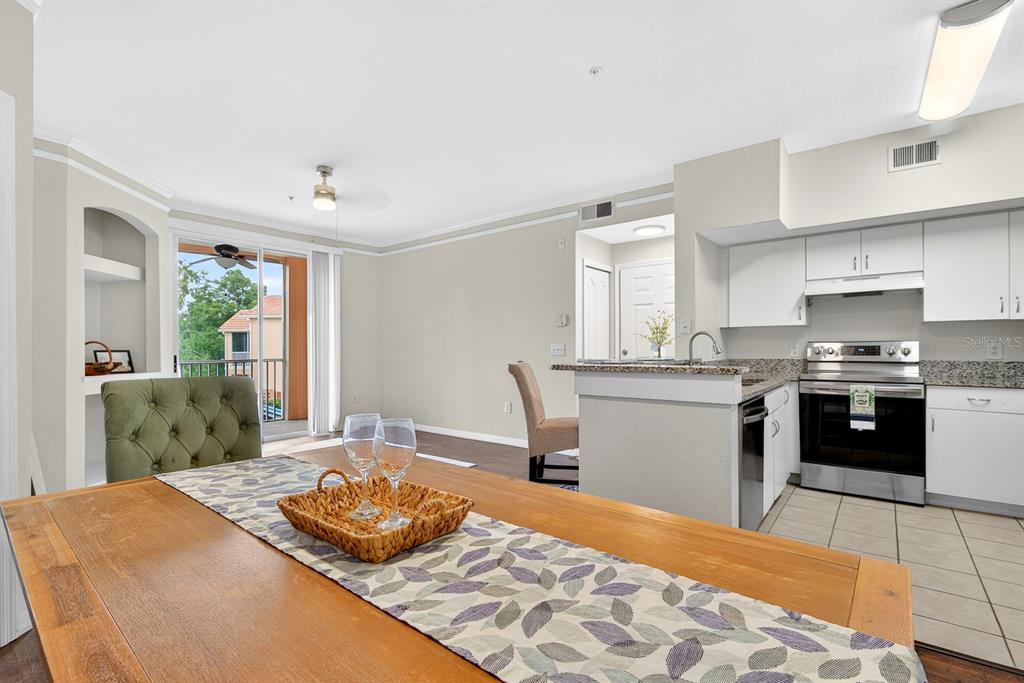 A dining area features a wooden table with wine glasses, a woven tray, and sliding doors — 4142 CENTRAL SARASOTA PARKWAY UNIT 1426, SARASOTA, FL