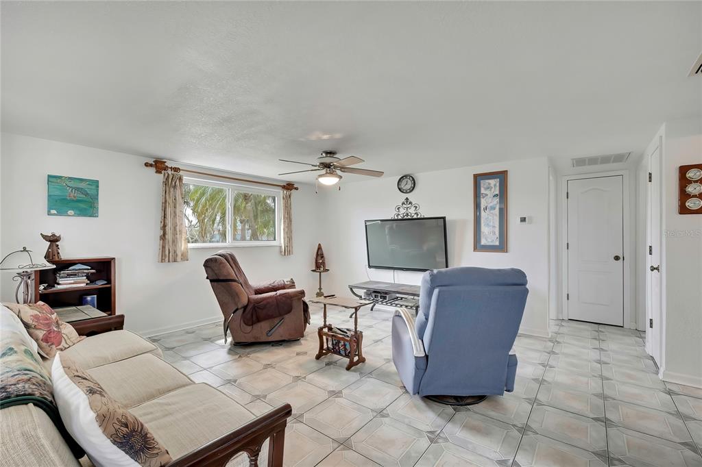 A living room features tile flooring, a ceiling fan, a television, and three chairs — 6601 SEA RANCH DRIVE, HUDSON, FL