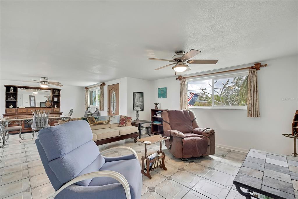 A living room with tile floors, two ceiling fans, a sofa, and two armchairs — 6601 SEA RANCH DRIVE, HUDSON, FL