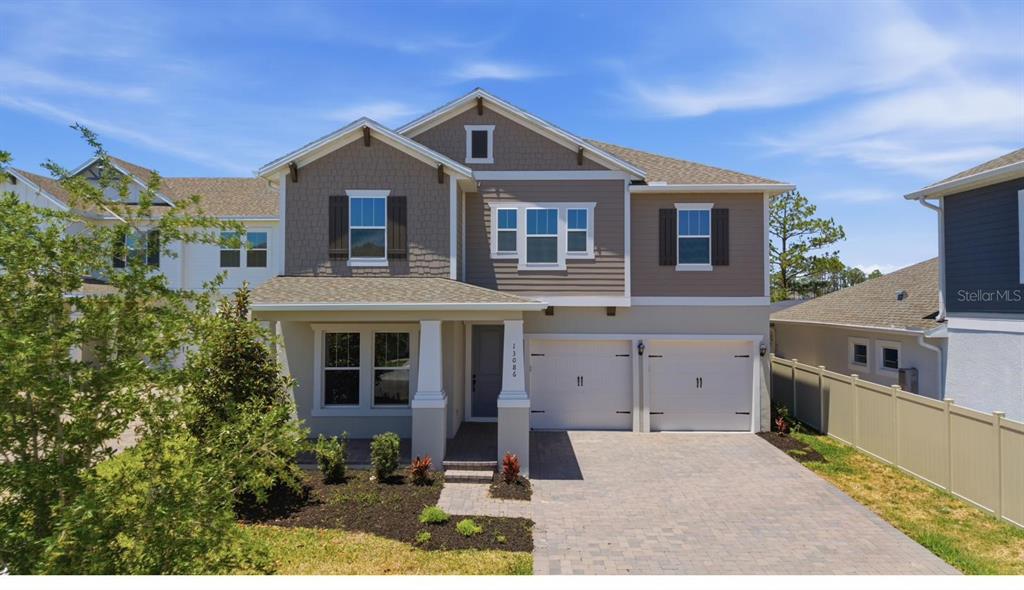 A two-story suburban house with a two-car garage, gray siding, and a paved driveway — 13086 SUNRISE HARVEST DRIVE, WINTER GARDEN, FL