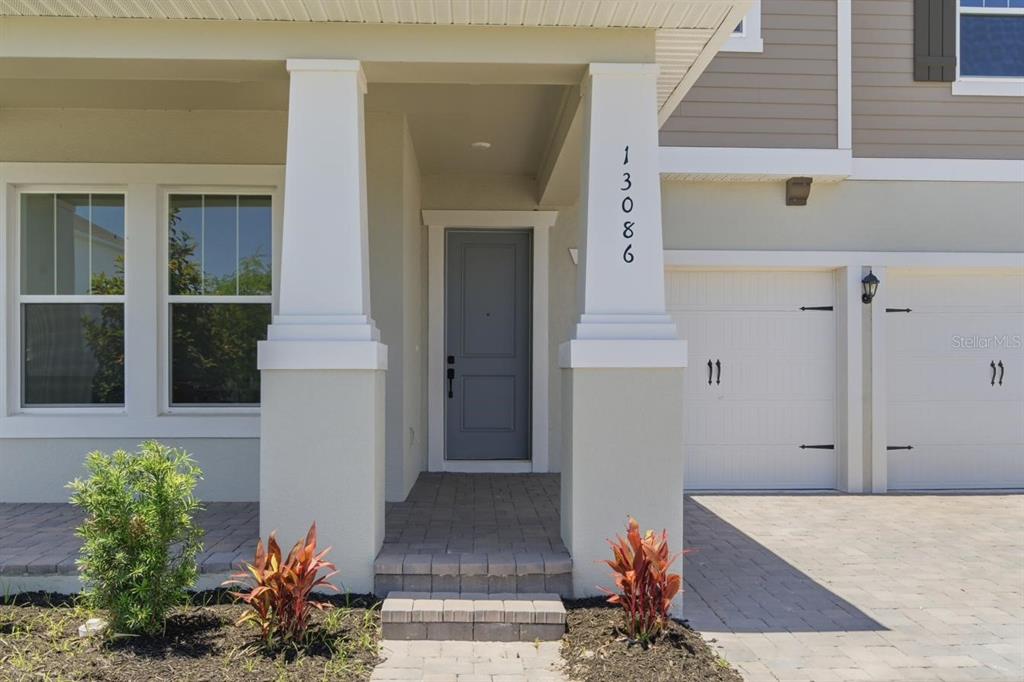 The exterior of a house features a gray front door, white columns, and a garage — 13086 SUNRISE HARVEST DRIVE, WINTER GARDEN, FL