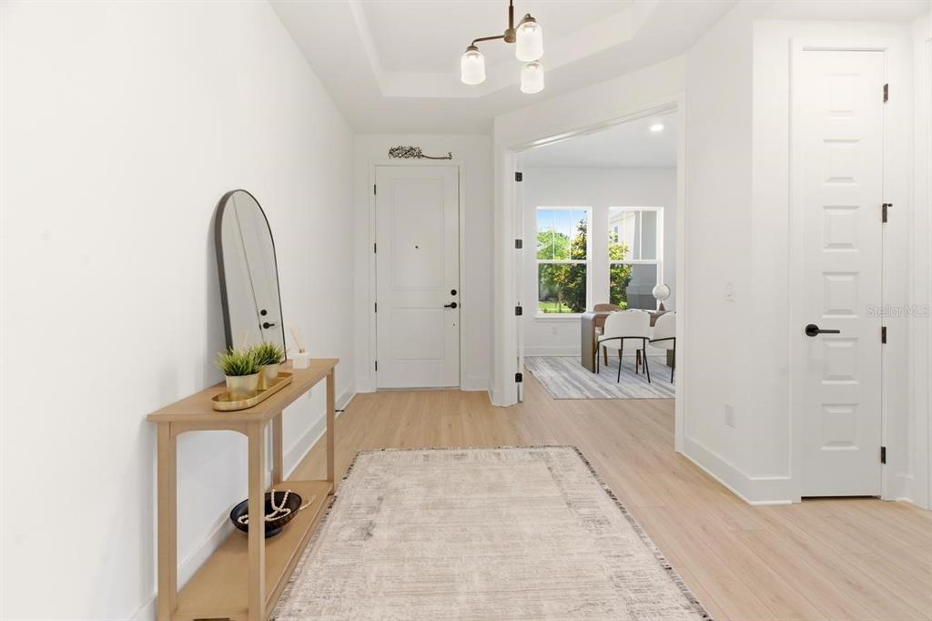 A bright entryway features light wood flooring, a console table with a mirror, and a rug — 13086 SUNRISE HARVEST DRIVE, WINTER GARDEN, FL