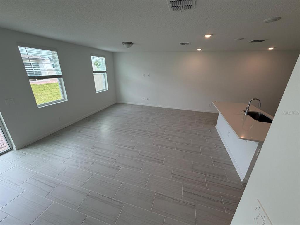 An open-concept living area features light gray wood-look tile flooring and a kitchen island — 4256 RANCH HOUSE ROAD, ST CLOUD, FL