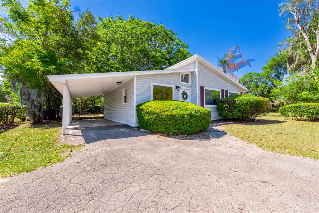 A light gray house with a carport, a large front bush, and a paved driveway — 950 S LAWRENCE BOULEVARD, KEYSTONE HEIGHTS, FL