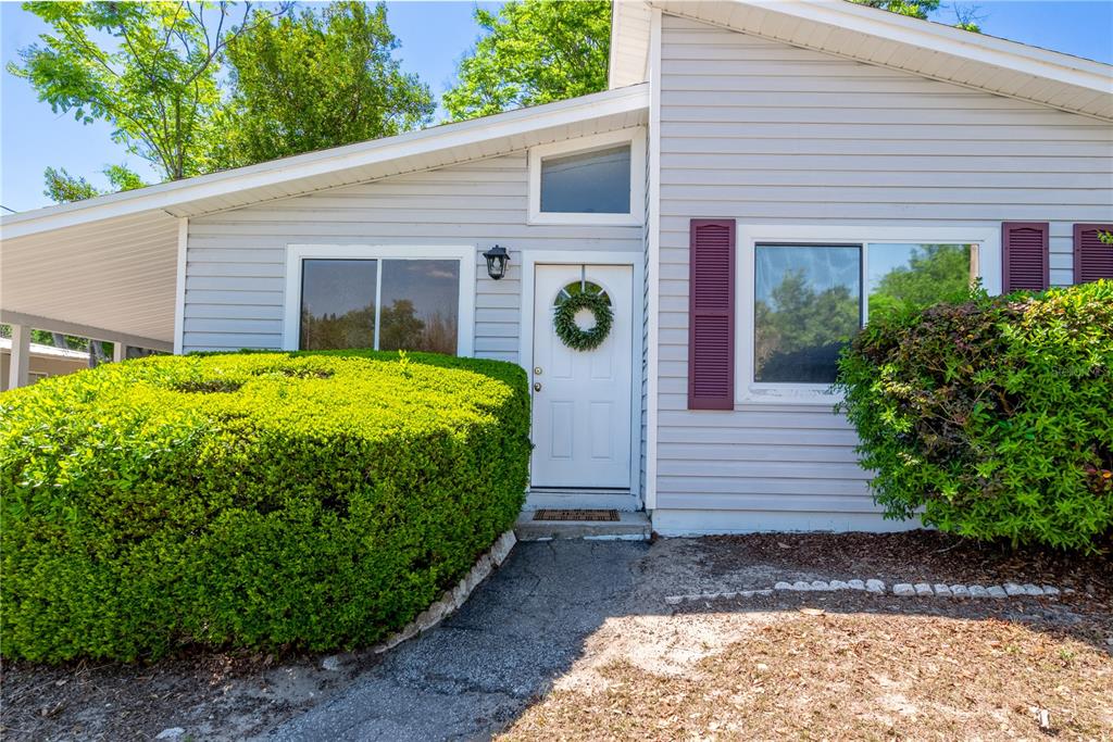 The exterior of a light gray house features a white front door and large bushes — 950 S LAWRENCE BOULEVARD, KEYSTONE HEIGHTS, FL