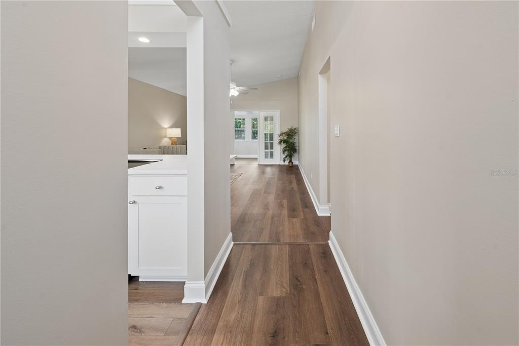 A hallway with wood-look flooring leads toward a living area with glass doors — 950 S LAWRENCE BOULEVARD, KEYSTONE HEIGHTS, FL