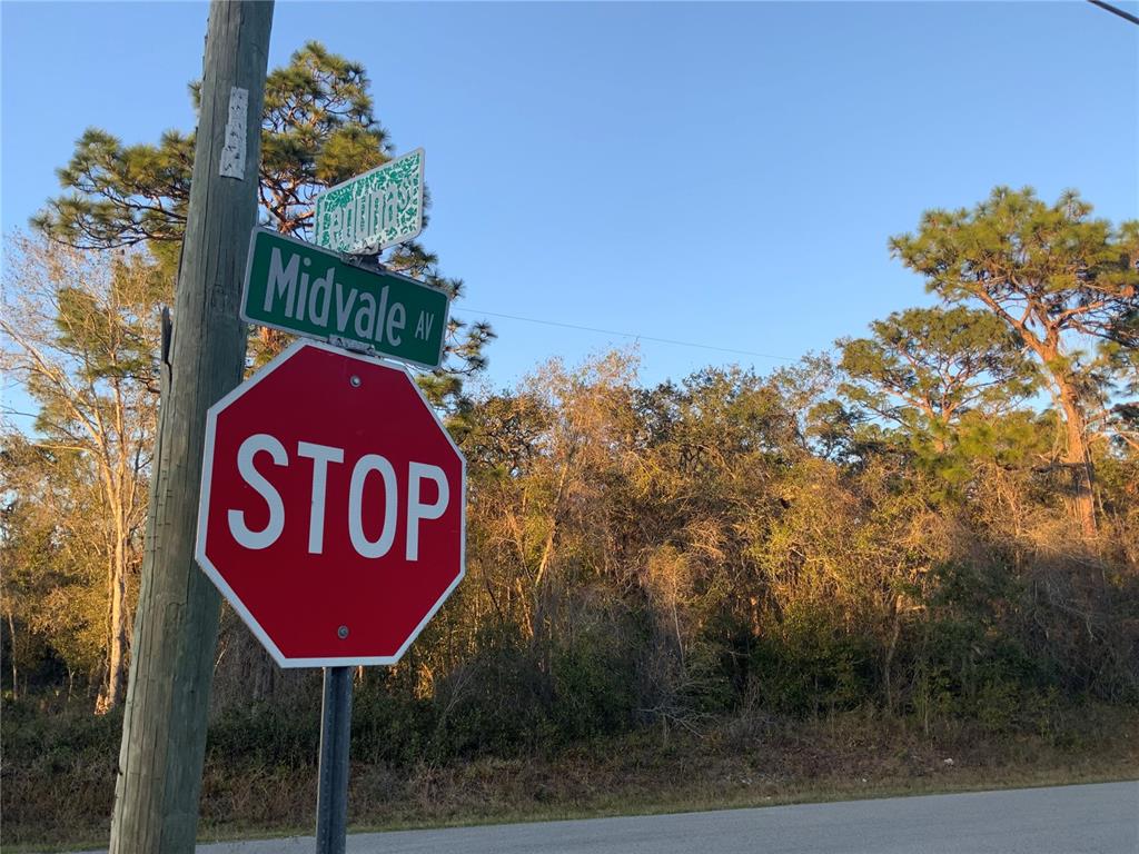 A stop sign and street sign for Midvale Avenue stand on a wooden utility pole — 12842 MIDVALE AVENUE, NEW PORT RICHEY, FL