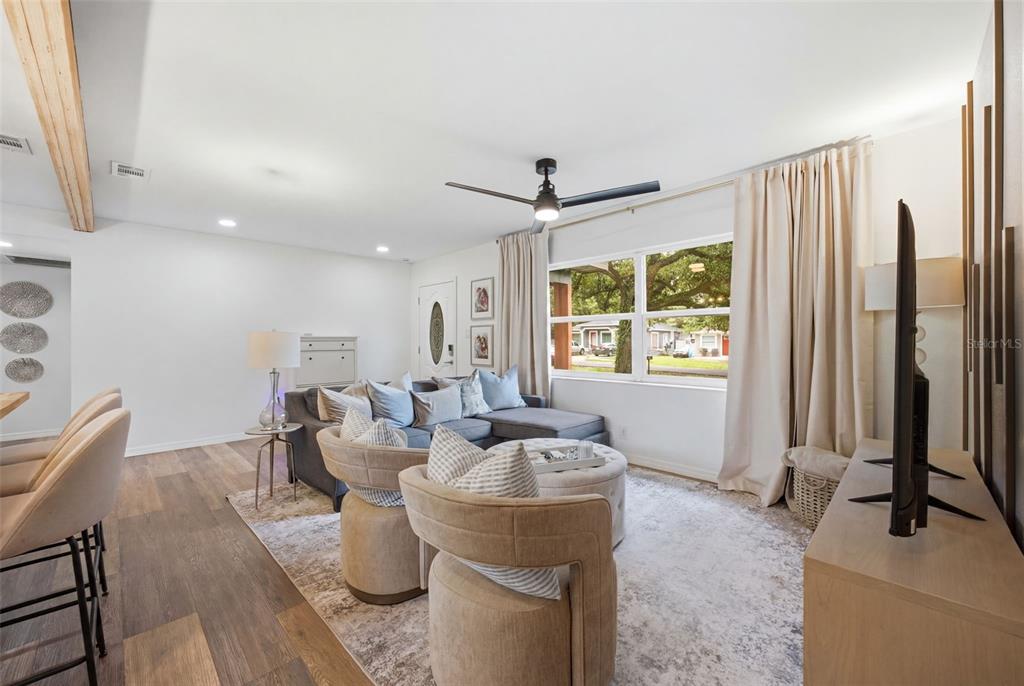 A living room features wood-look flooring, a sectional sofa, two armchairs, and a ceiling fan — 8719 N TEMPLE AVENUE, TAMPA, FL