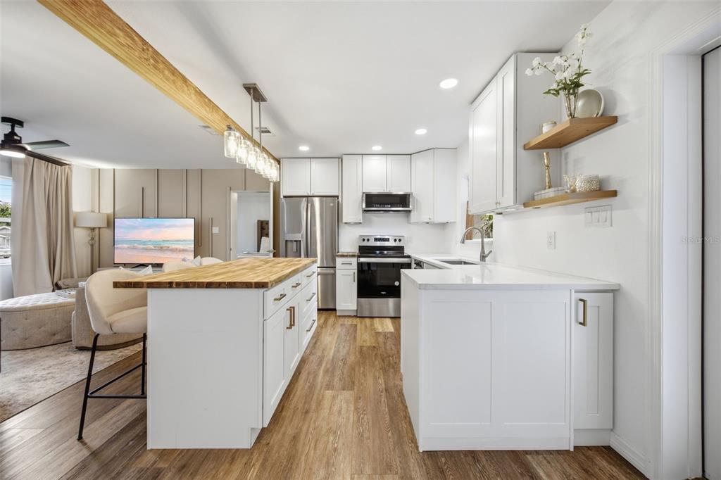 A modern kitchen features white cabinets, a wood-topped island, and stainless steel appliances — 8719 N TEMPLE AVENUE, TAMPA, FL