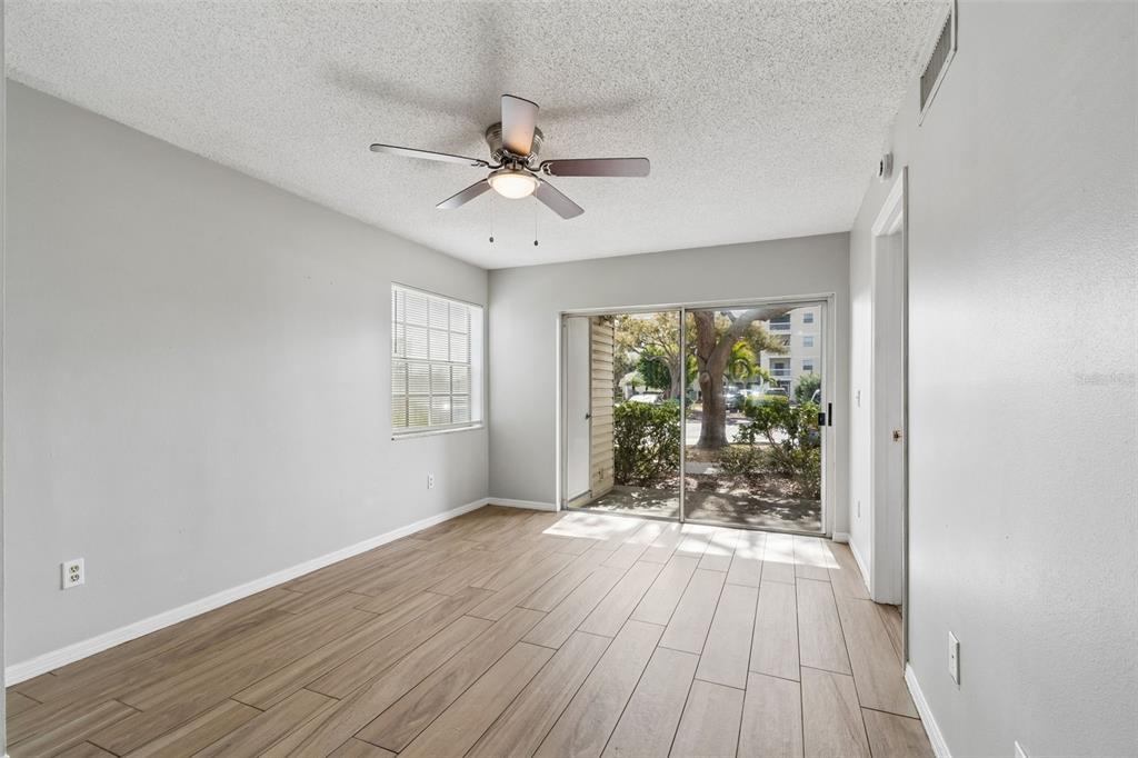An empty room with light wood-look tile flooring, a ceiling fan, and a sliding glass door — 6915 STONES THROW CIRCLE N UNIT 3106, ST PETERSBURG, FL