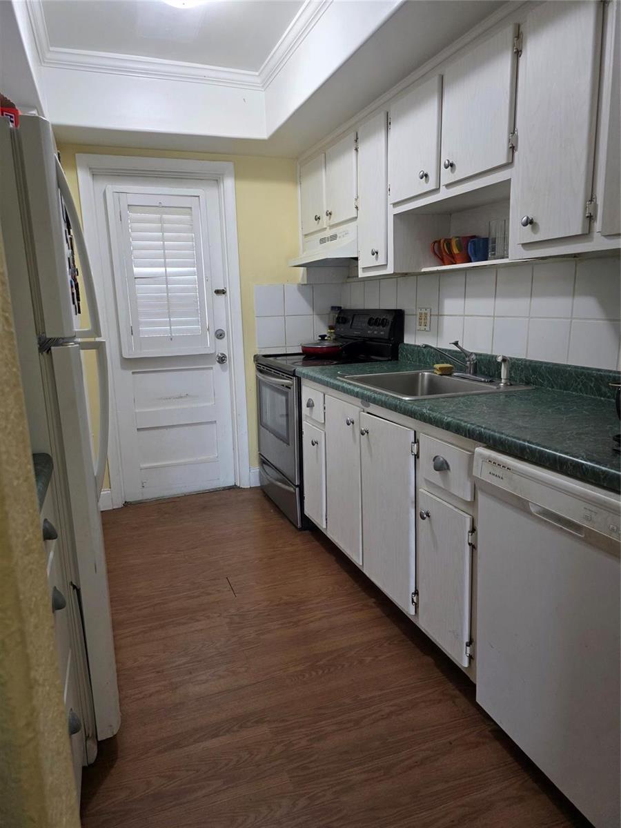A galley kitchen features white cabinets, green laminate countertops, and wood-look flooring — 5800 Margate Boulevard # 347, Pompano Beach FL 33063, POMPANO BEACH, FL