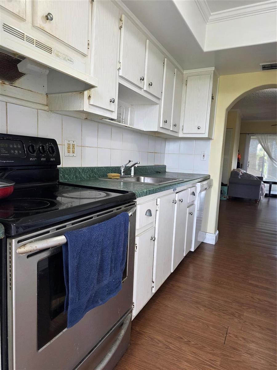 A kitchen features white cabinets, a black stove, green countertops, and wood-look flooring — 5800 Margate Boulevard # 347, Pompano Beach FL 33063, POMPANO BEACH, FL