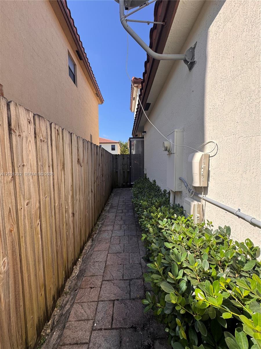 A narrow paved walkway runs between a wooden fence and the side of a house — 15400 SW 173rd St # 2, Miami FL 33187, MIAMI, FL