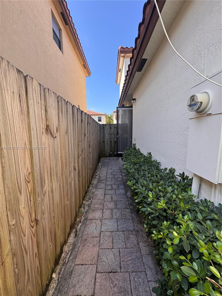 A narrow paved walkway runs between a wooden fence and the side of a house — 15400 SW 173rd St # 2, Miami FL 33187, MIAMI, FL