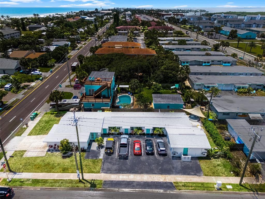 An aerial view shows a single-story apartment building with a parking lot and swimming pool — 402 S ORLANDO AVENUE, COCOA BEACH, FL