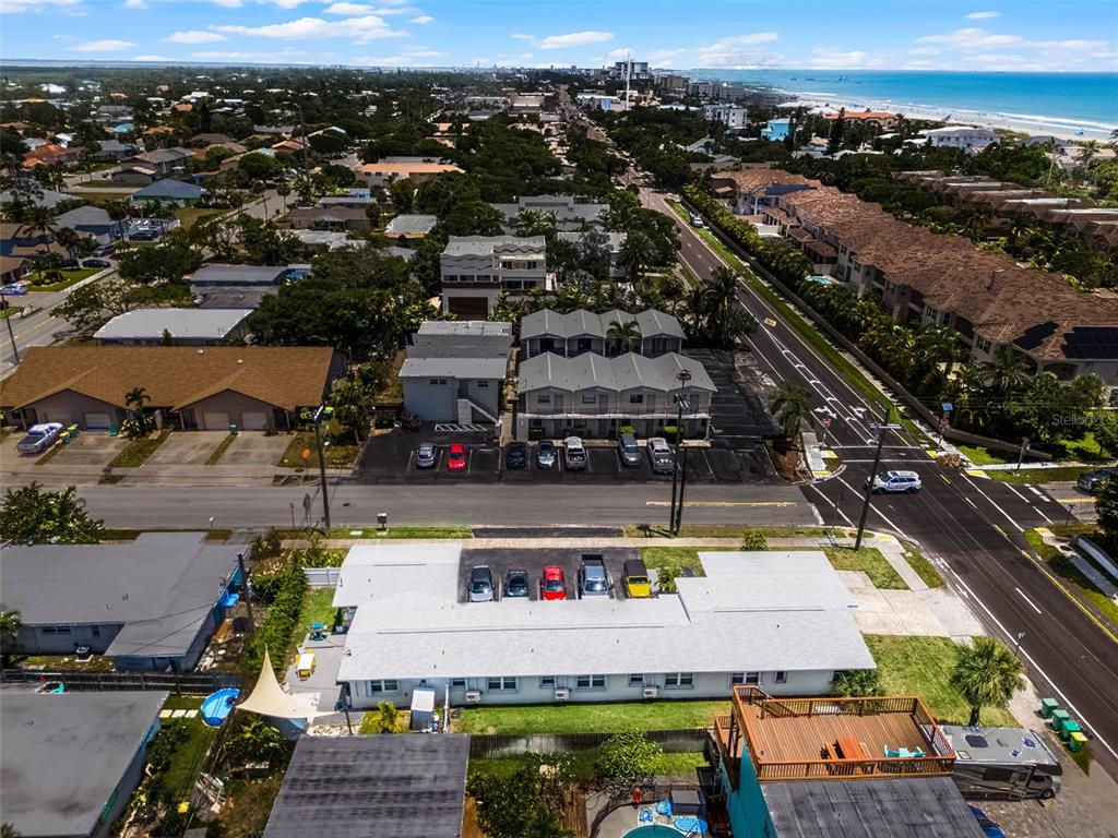 An aerial view shows a multi-unit residential building with a parking lot and nearby beach — 402 S ORLANDO AVENUE, COCOA BEACH, FL