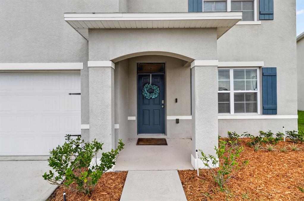 The exterior of a house features a blue front door, a covered entryway, and a garage — 2767 GRANDBURY GROVE ROAD, LAKELAND, FL
