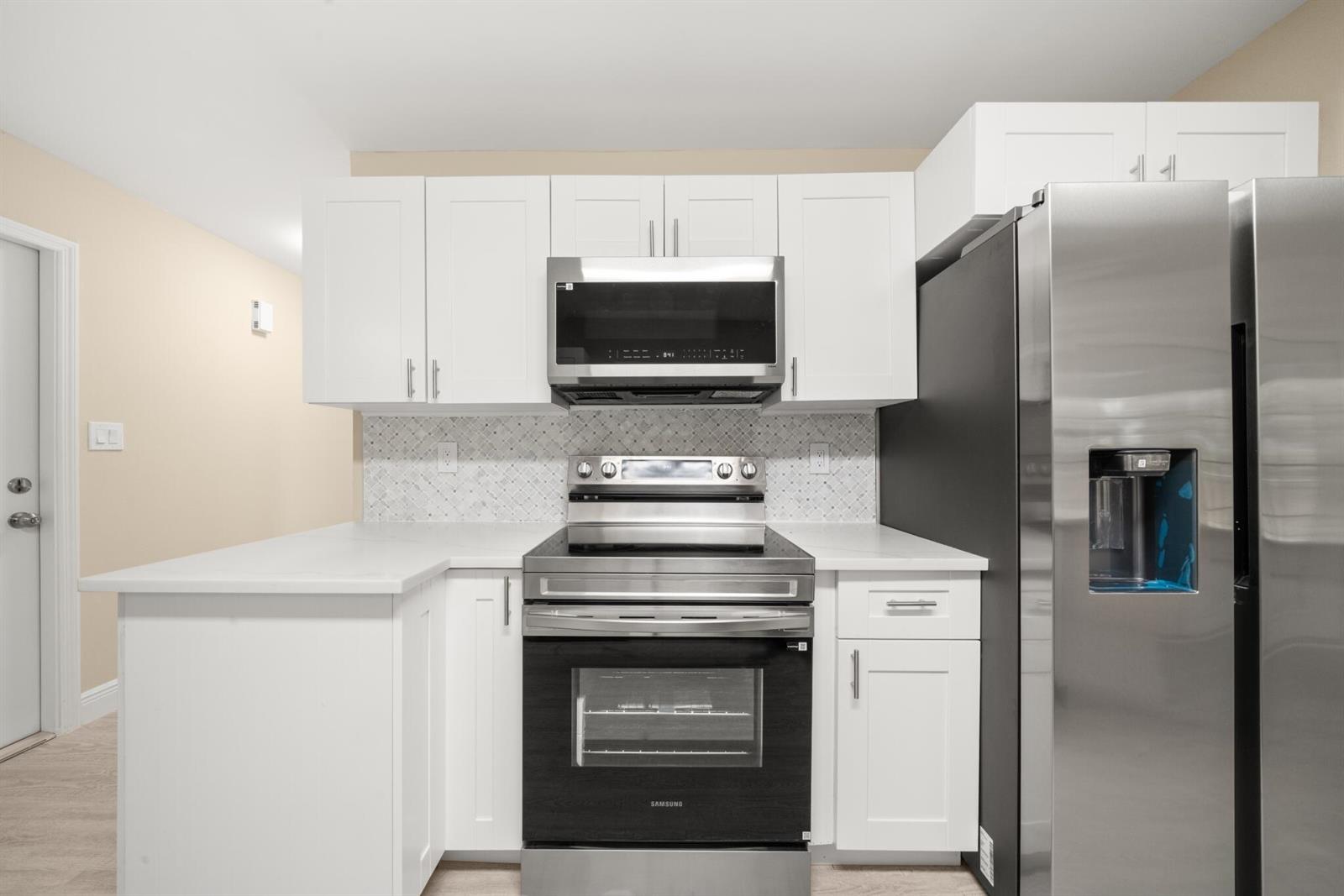 A kitchen features white cabinets, stainless steel appliances, and a tiled backsplash — 4119 Tangier Street, Sebring FL 33872, SEBRING, FL