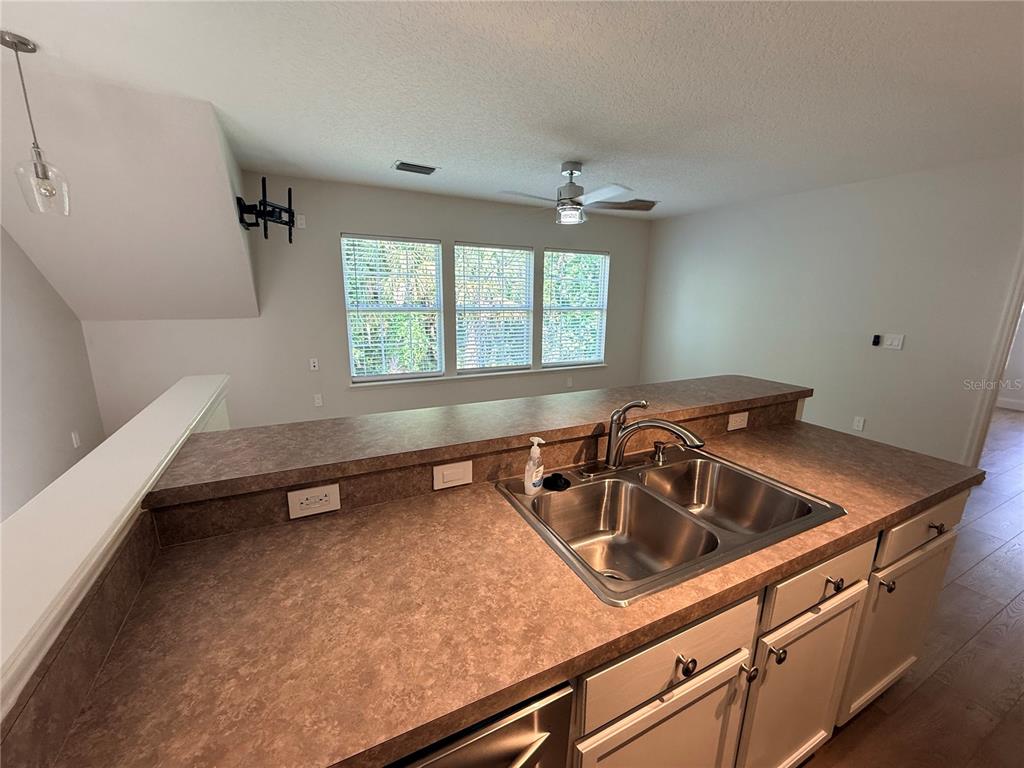 A kitchen features a double-basin sink, laminate countertops, and white cabinets — 1005 KESTREL COURT UNIT B, CELEBRATION, FL