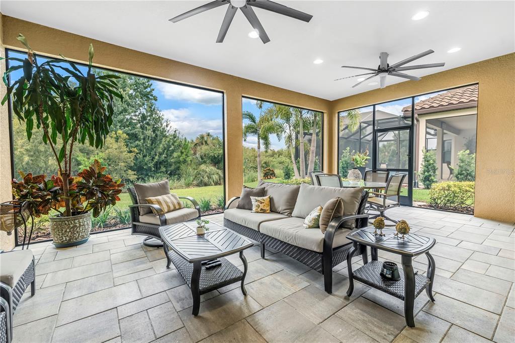 A screened-in patio features tile flooring, outdoor furniture, ceiling fans, and views of landscaping — 9912 BATCHELDER TERRACE, PALMETTO, FL