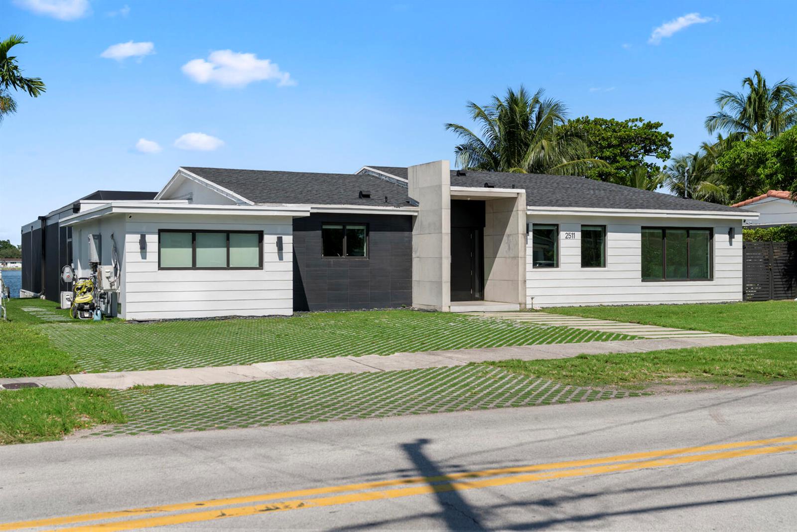 A modern single-story house with white siding, dark accents, and a concrete entryway — 2511 NE 209th Terrace, Miami FL 33180, MIAMI, FL