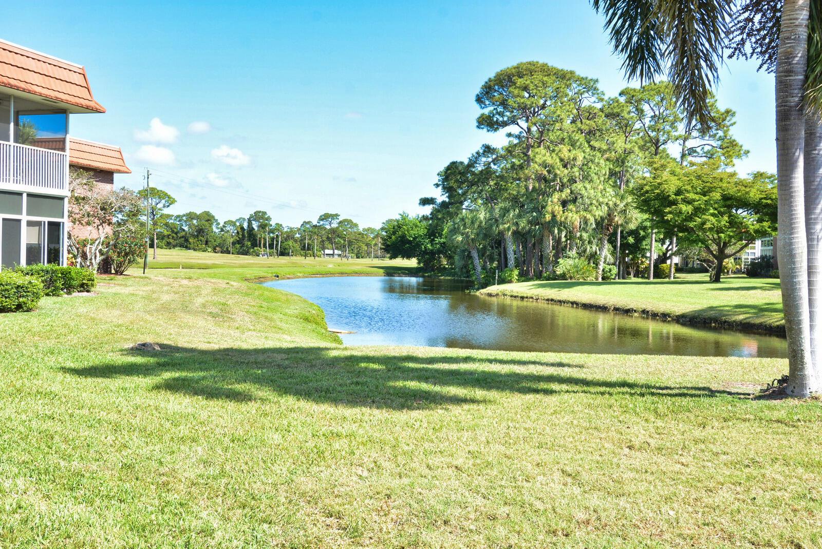 A view of a pond and green lawn next to a multi-story residential building — 1225 NW 21st Street # 1701, Stuart FL 34994, STUART, FL