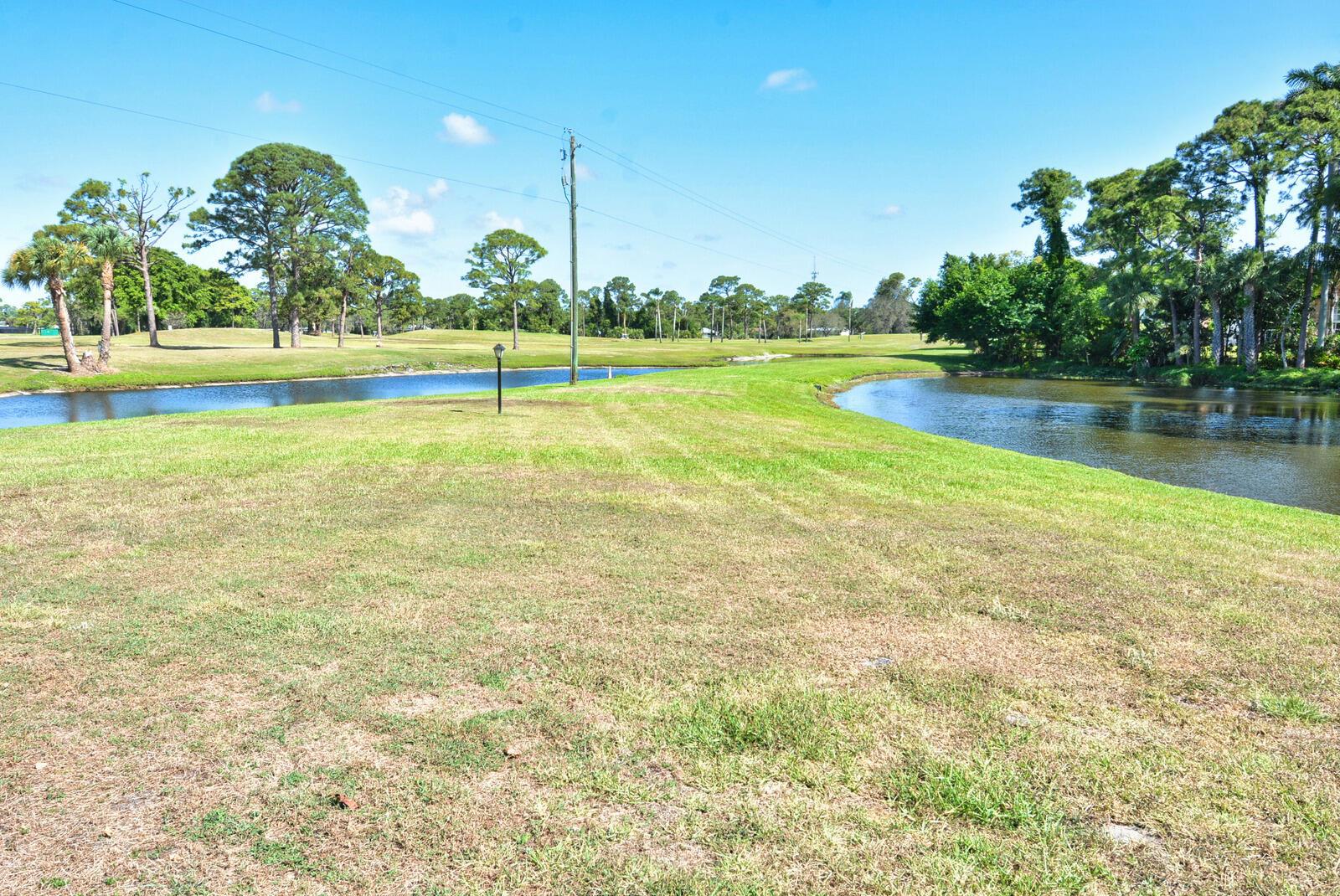 A grassy lawn stretches between two ponds on a sunny day with scattered trees — 1225 NW 21st Street # 1701, Stuart FL 34994, STUART, FL