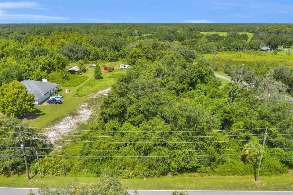 An aerial view shows a rural property with a metal building, trees, and open fields — 292 N FORT CHRISTMAS ROAD, CHRISTMAS, FL