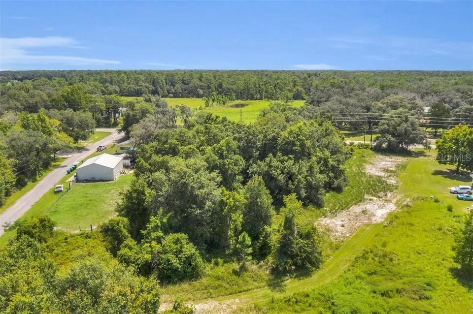 An aerial view shows a rural property with a house, a garage, and wooded areas — 292 N FORT CHRISTMAS ROAD, CHRISTMAS, FL