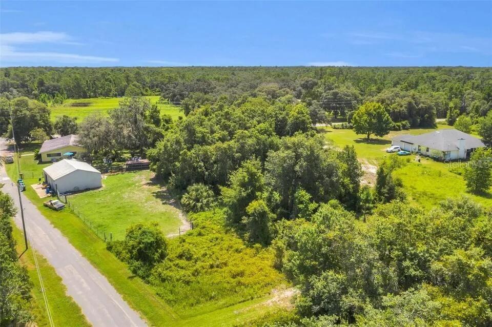 An aerial view shows a large, grassy lot with trees and a nearby residential house — 292 N FORT CHRISTMAS ROAD, CHRISTMAS, FL