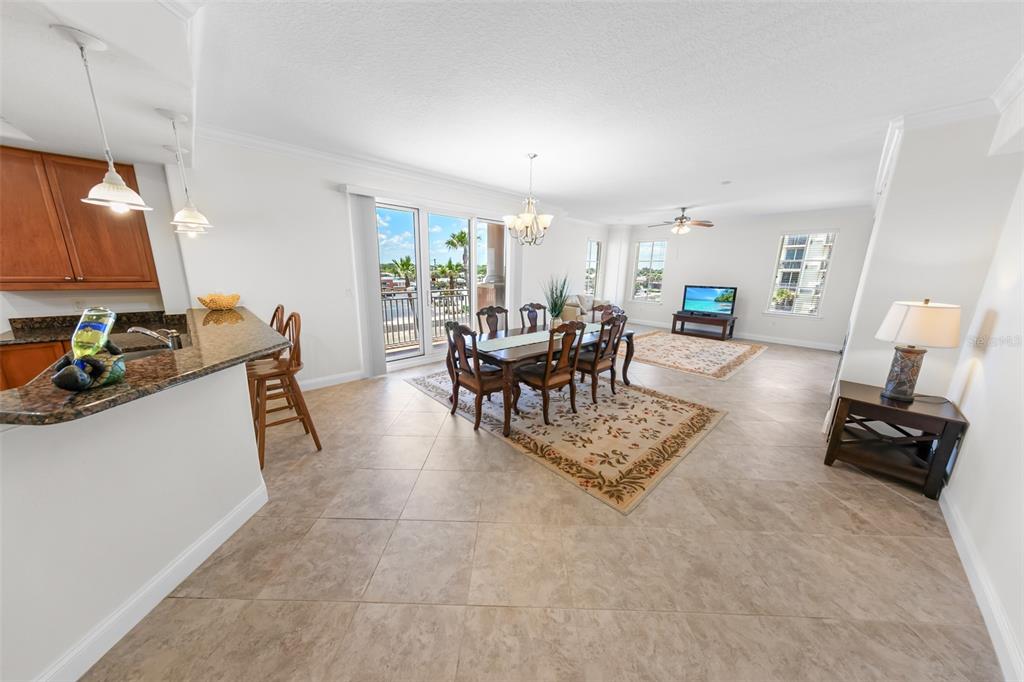 An open-concept dining and living area features tile flooring, a kitchen island, and balcony access — 2515 S ATLANTIC AVENUE UNIT 301, DAYTONA BEACH, FL