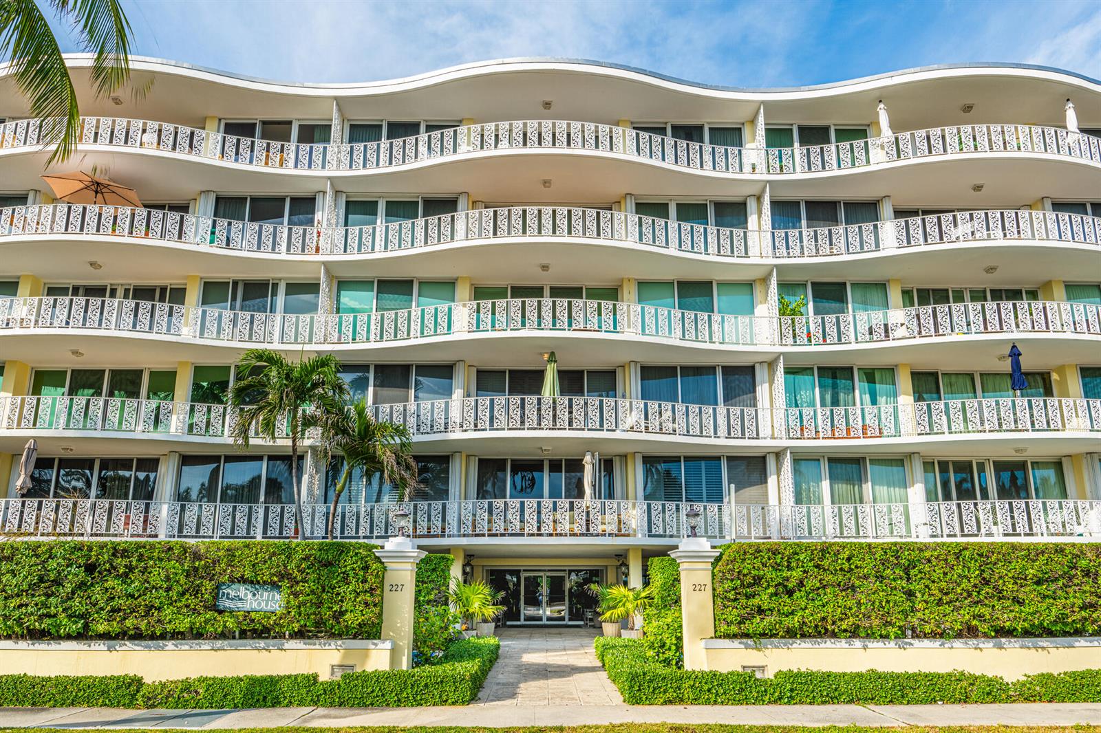 A multi-story apartment building features curved balconies with white railings and a landscaped entrance — 227 Australian Avenue # 2c, Palm Beach FL 33480, PALM BEACH, FL