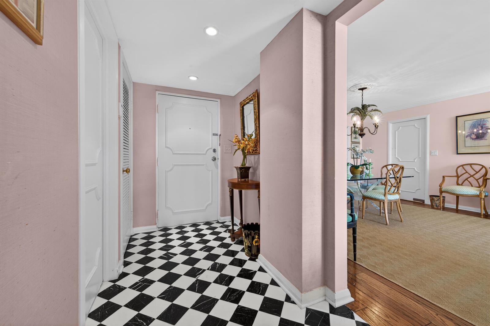 An entryway with a black and white checkered floor leads into a pink-walled dining room — 227 Australian Avenue # 2c, Palm Beach FL 33480, PALM BEACH, FL