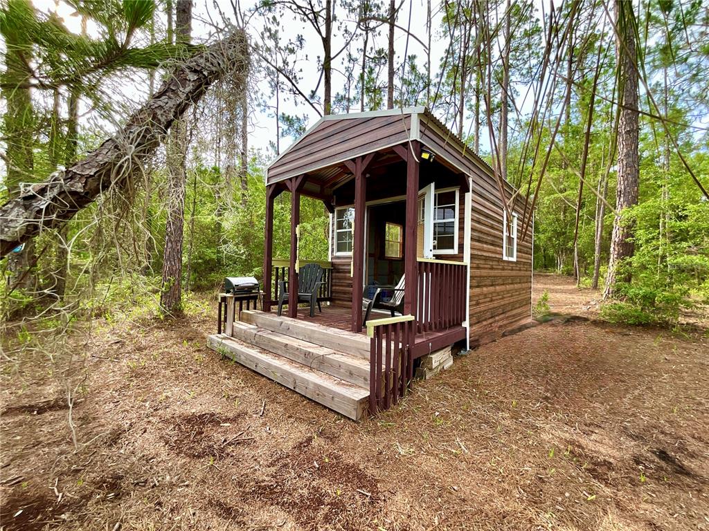 A small wooden cabin with a front porch sits in a wooded area — 125 SILVER DOLLAR POND ROAD, HAWTHORNE, FL