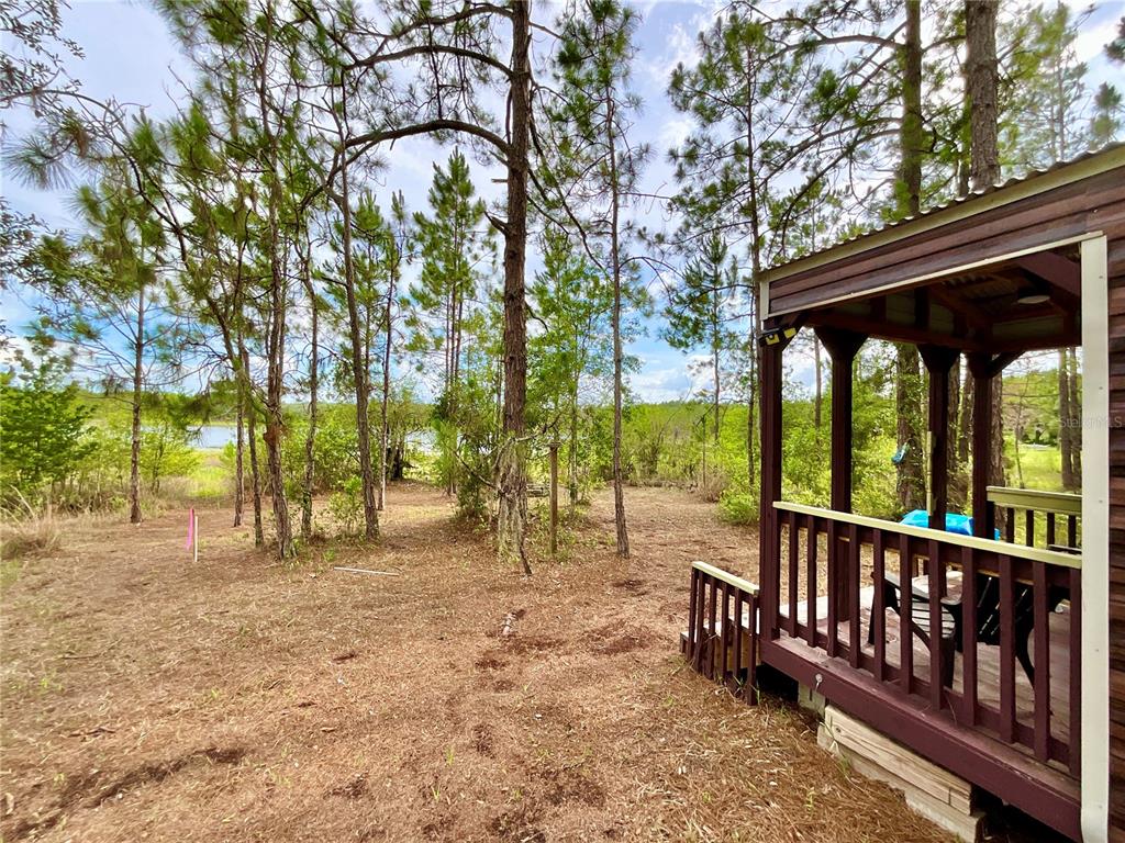 A wooden porch overlooks a wooded yard with a view of a distant lake — 125 SILVER DOLLAR POND ROAD, HAWTHORNE, FL