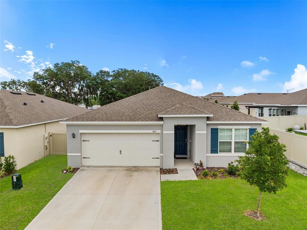 A single-story house with a gray stucco exterior, a two-car garage, and a shingled roof — 1421 CUMBERLAND AVENUE, DAVENPORT, FL