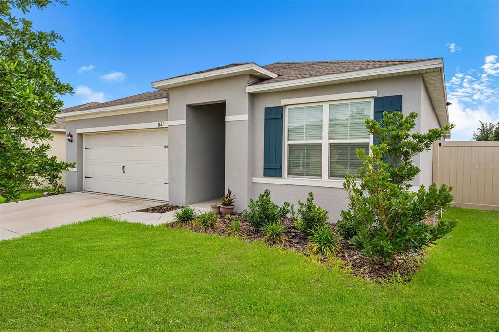 A single-story house with a gray stucco exterior, a two-car garage, and blue window shutters — 1421 CUMBERLAND AVENUE, DAVENPORT, FL
