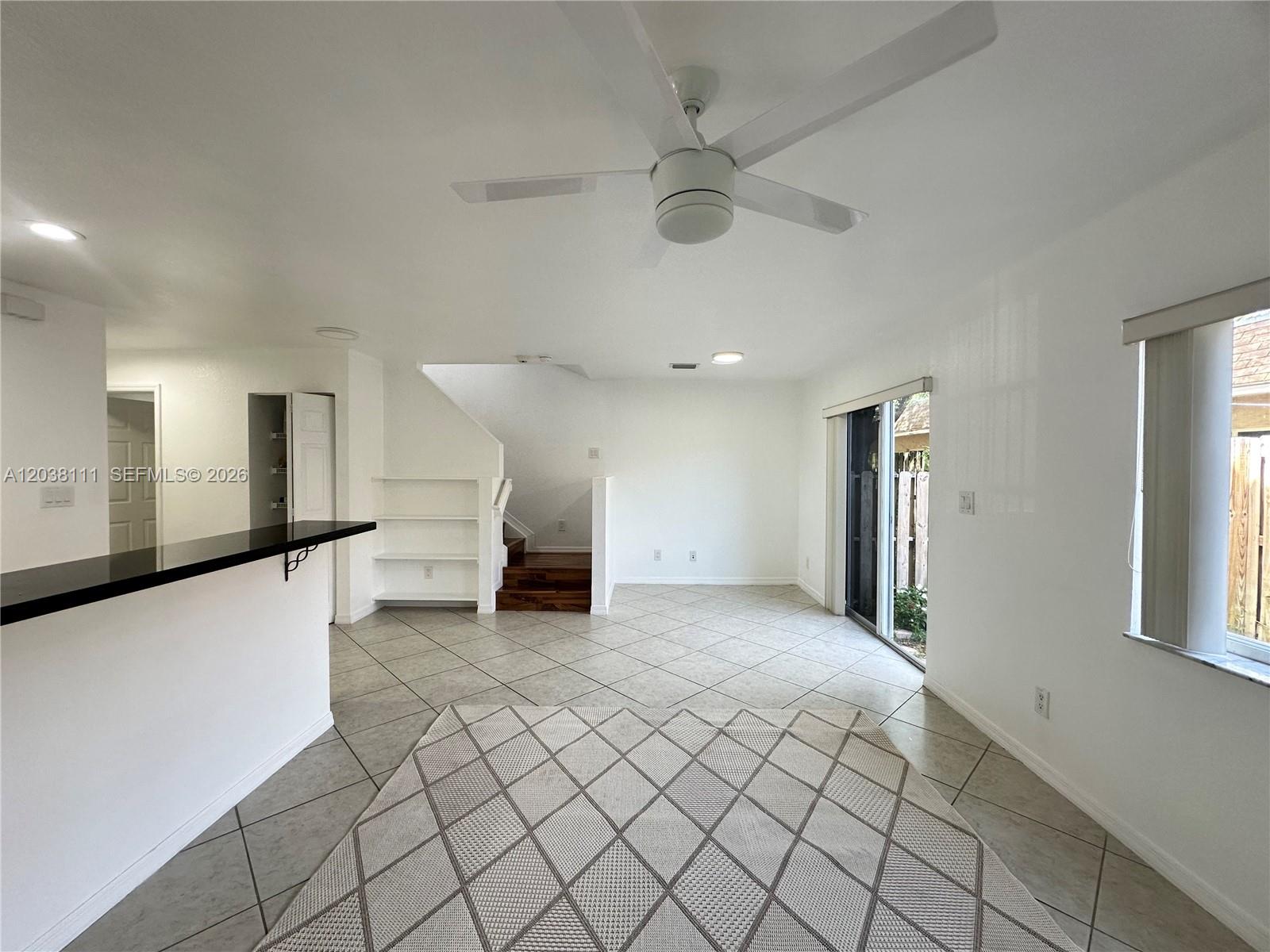 A living area features tile floors, a ceiling fan, a staircase, and a sliding glass door — 324 NE 3rd St # D, Hallandale Beach FL 33009, HALLANDALE BEACH, FL