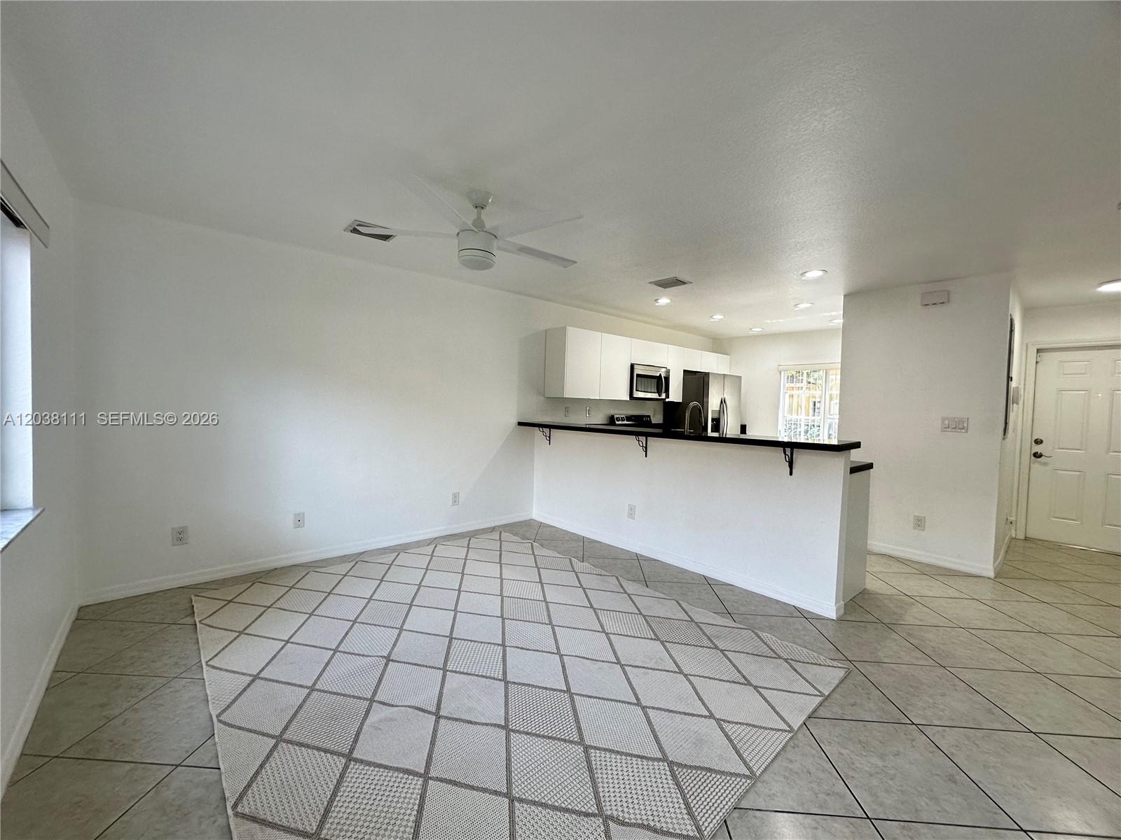 An open-concept living area features tile flooring, a white kitchen, and a breakfast bar — 324 NE 3rd St # D, Hallandale Beach FL 33009, HALLANDALE BEACH, FL
