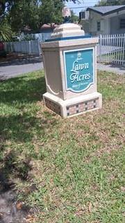 A beige monument sign for Lawn Acres stands on a grassy lawn near a white fence — 5620 Monroe Street, Hollywood FL 33023, HOLLYWOOD, FL