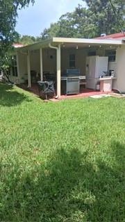 A covered patio with a grill and outdoor refrigerator overlooks a grassy backyard — 5620 Monroe Street, Hollywood FL 33023, HOLLYWOOD, FL
