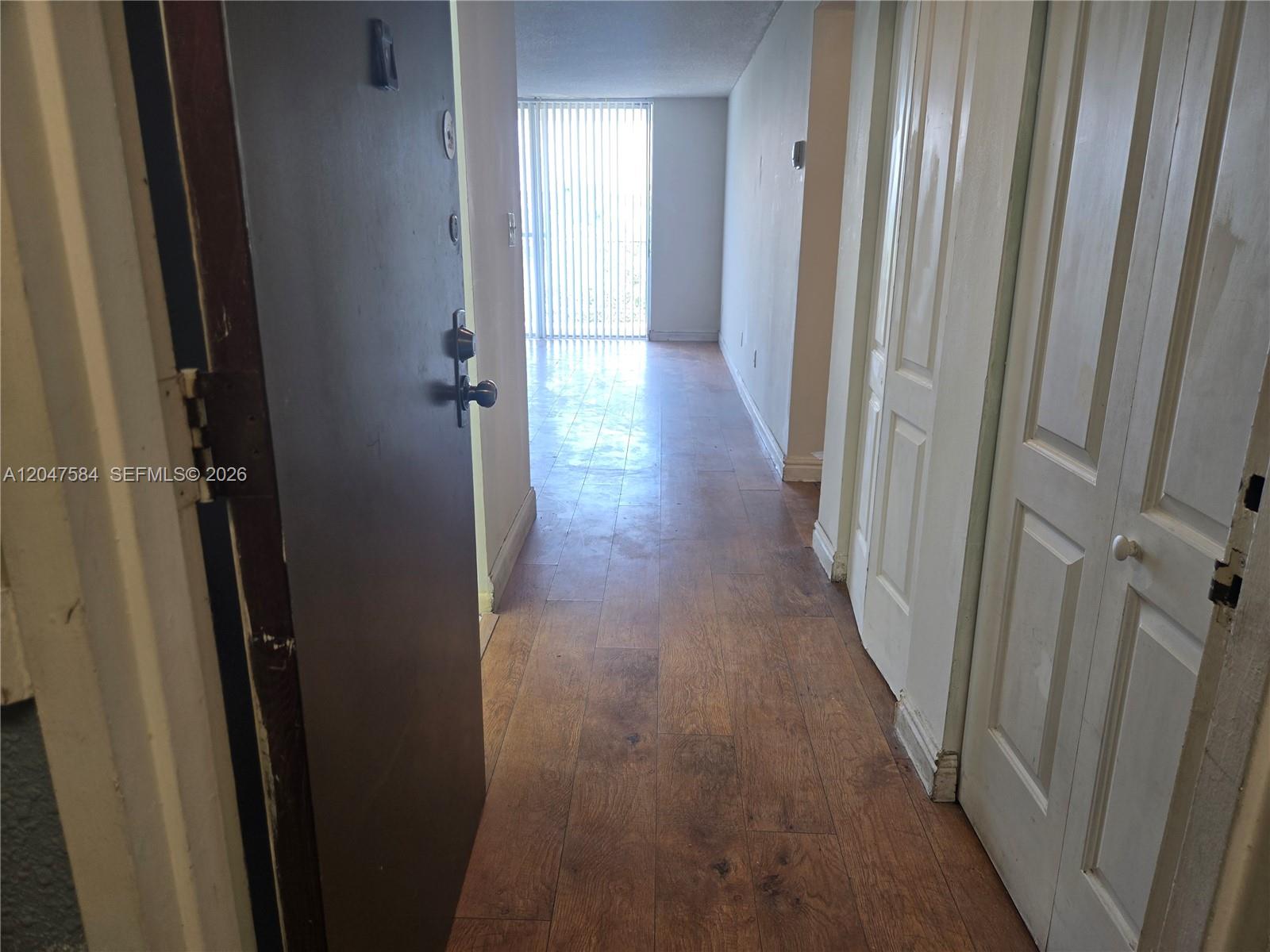 An entryway leads into a hallway with wood-look flooring and white paneled closet doors — 482 NW 165th St Rd # 505, Miami FL 33169, MIAMI, FL