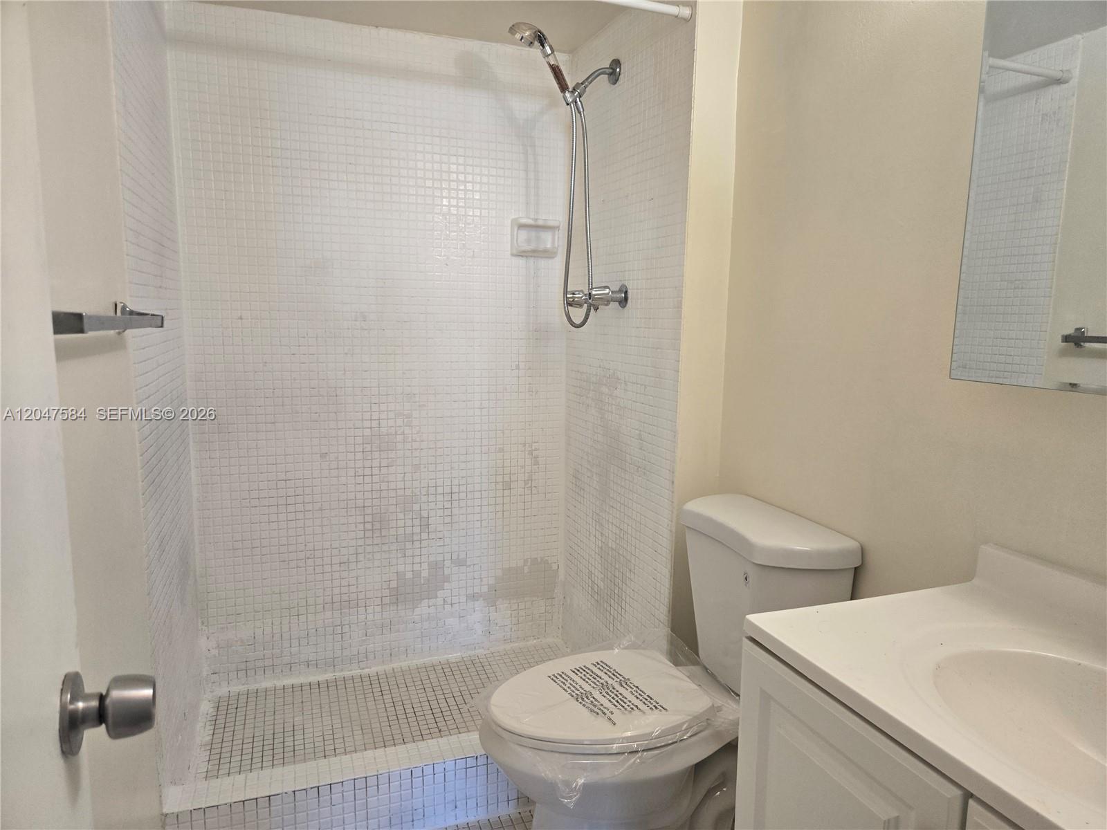 A small bathroom features a tiled walk-in shower, a toilet, and a vanity sink — 482 NW 165th St Rd # 505, Miami FL 33169, MIAMI, FL