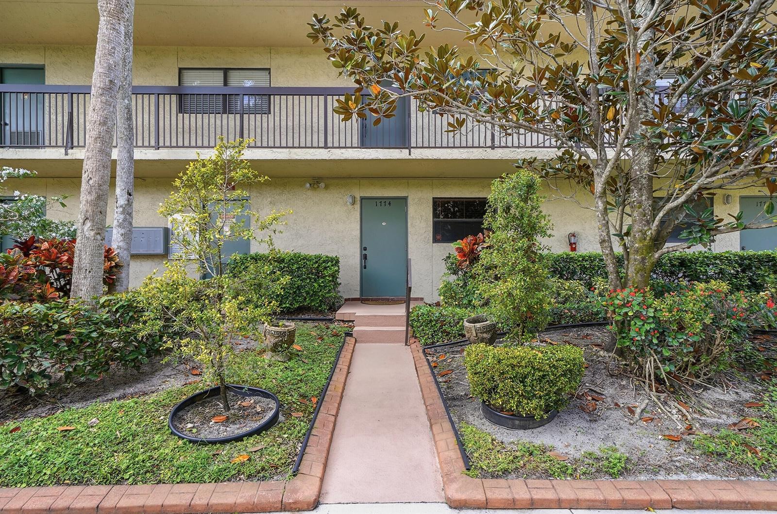 A ground-level apartment entrance with a walkway, landscaping, and a second-story balcony — 1774 Hammock Boulevard # 118, Coconut Creek FL 33063, COCONUT CREEK, FL