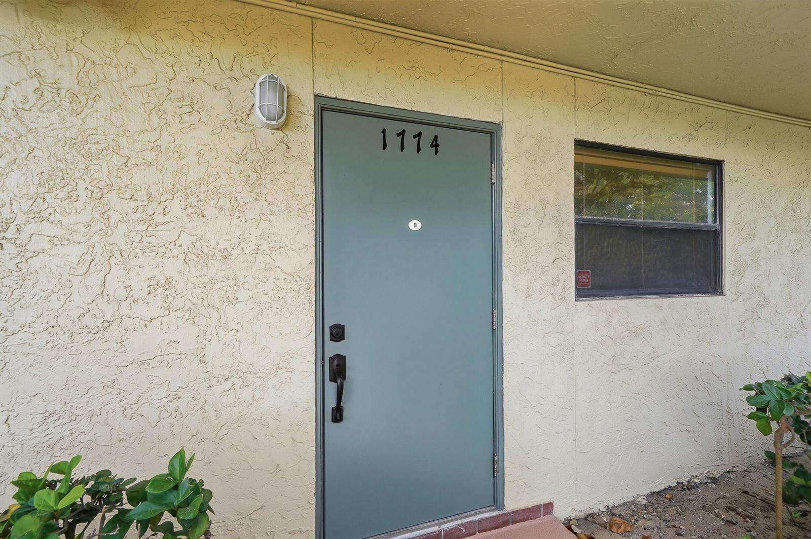 A teal front door with the number 1114 is set into a textured beige exterior wall — 1774 Hammock Boulevard # 118, Coconut Creek FL 33063, COCONUT CREEK, FL