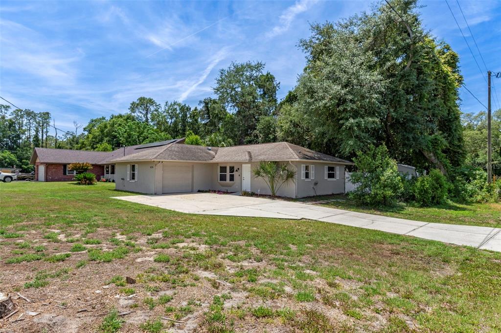 A single-story house with a concrete driveway and a garage under a blue sky — 6236 W PINEDALE CIRCLE, CRYSTAL RIVER, FL
