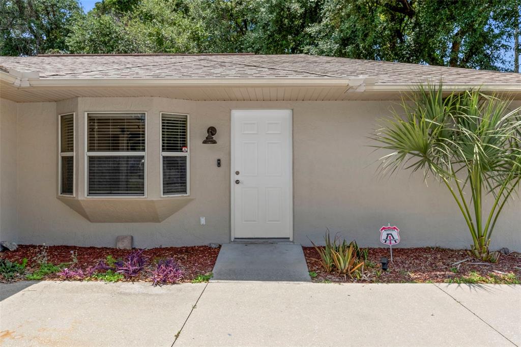 The exterior of a single-story home features a white front door, bay window, and landscaping — 6236 W PINEDALE CIRCLE, CRYSTAL RIVER, FL