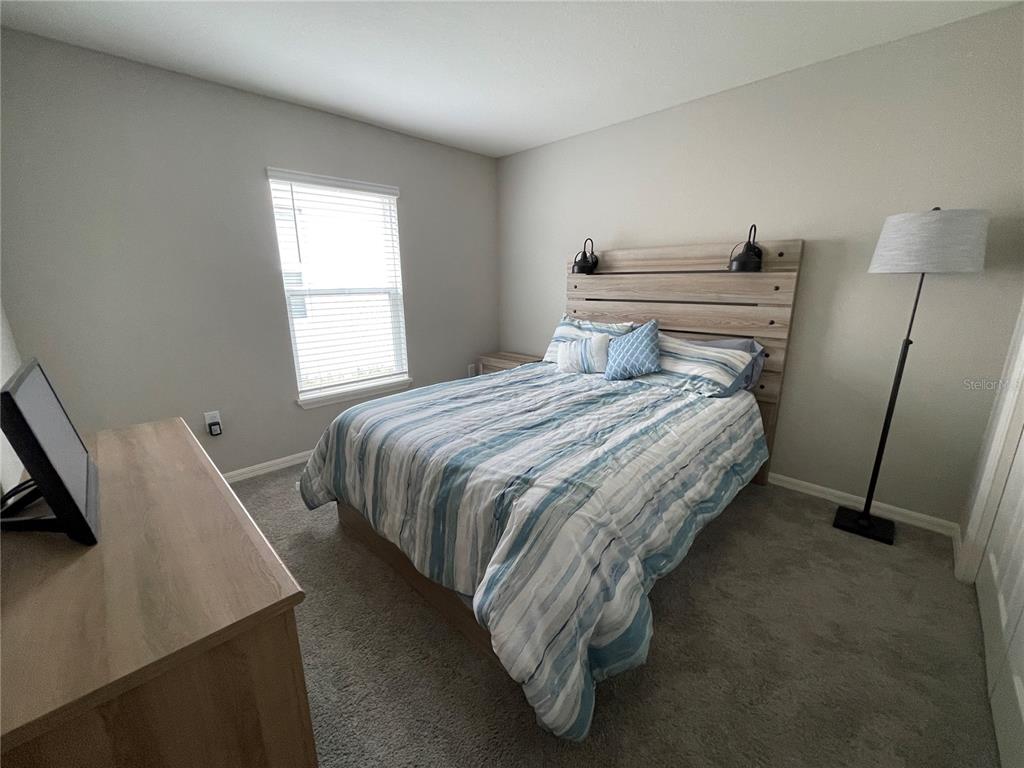 A bedroom features a wooden headboard, a blue striped comforter, and a floor lamp — 2824 SAN MARCO WAY, WINTER HAVEN, FL