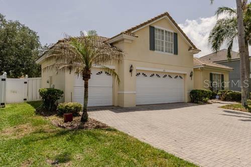 A two-story house with a beige stucco exterior, a two-car garage, and a paved driveway — 65 CALLIOPE STREET, OCOEE, FL