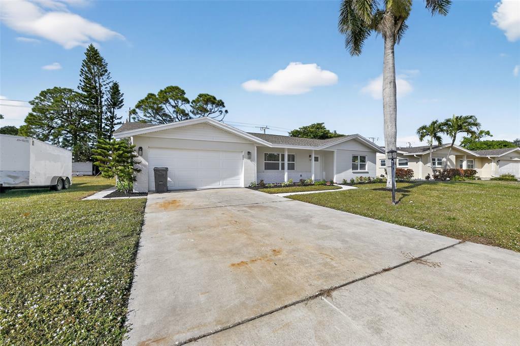 A single-story house with a white exterior, a two-car garage, and a concrete driveway — 6224 7TH AVENUE DRIVE W, BRADENTON, FL
